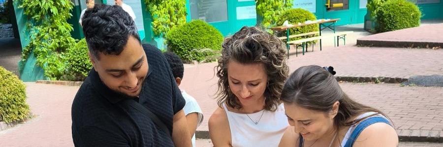 2026-08-28-KJA-Koeln-OezguerKacar-Ehrenamtlicher-FERIEN-ZU-HAUSE-Seeberg-Tatiane-Joner-jmd-Koeln-und-HilalKacar-Ehrenamtliche-FERIEN-ZU-HAUSE-Seeberg-beim-Anschnitt-der-Festtagstorte.jpg_608176444